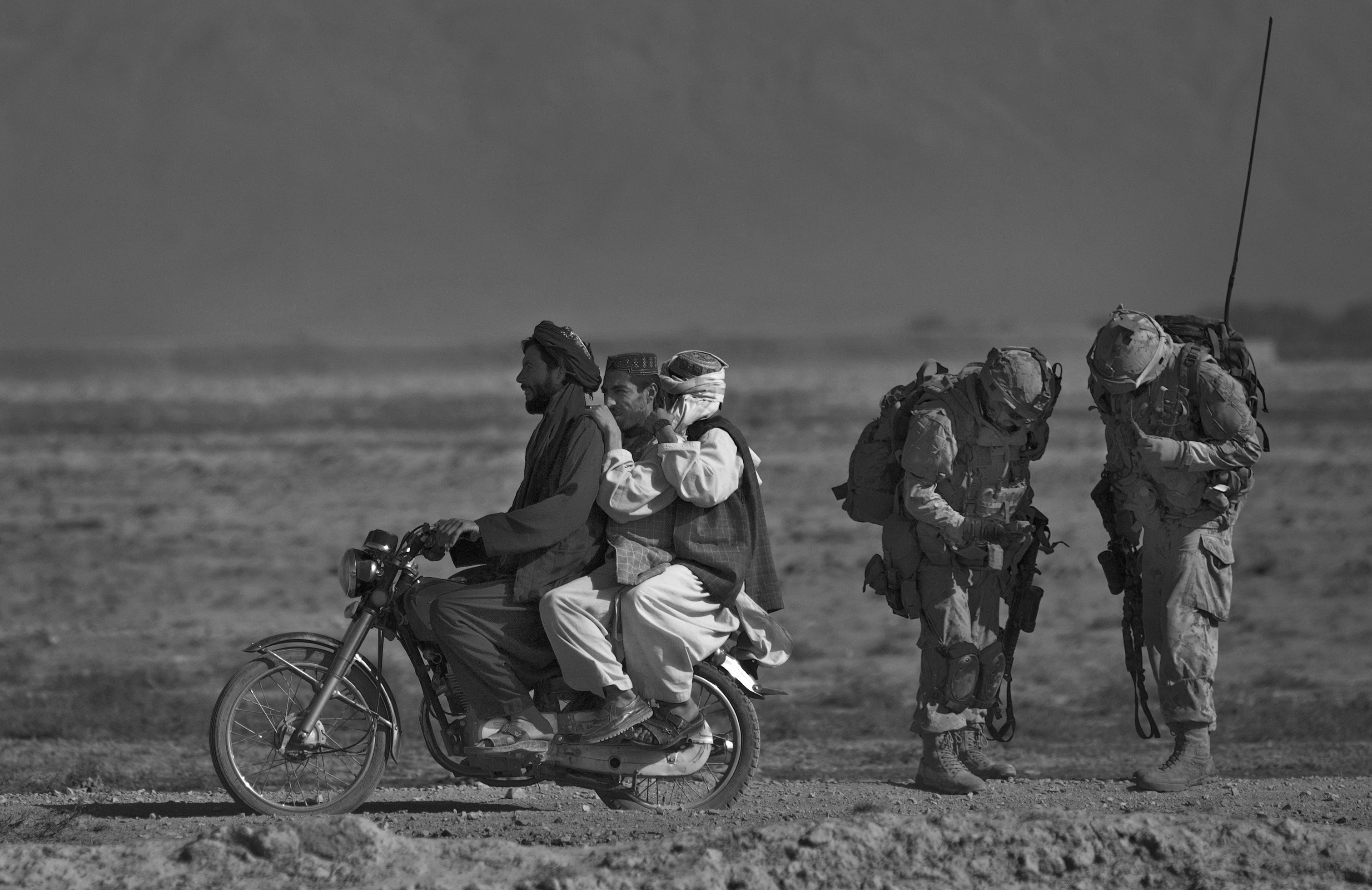 Anja Niedringhaus, Des Afghans à moto passent devant des soldats canadiens du Royal Canadian Regiment en patrouille dans le district de Panjwai, au sud-ouest de Kandahar. Salavat, Afghanistan, septembre 2010 © Anja Niedringhaus/AP/SIPA