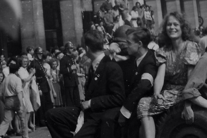 Des jeunes gens descendent à la suite du général de Gaulle dans la rue de Rivoli pavoisée aux couleurs des Alliés. Paris, 26 août 1944.