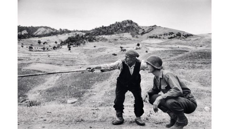 Un paysan sicilien indique à un officier américain la direction prise par les Allemands, près de Troina en Sicile, Italie, Août 1943 Crédit : Robert Capa/ International Center of Photography/Magnum Photos